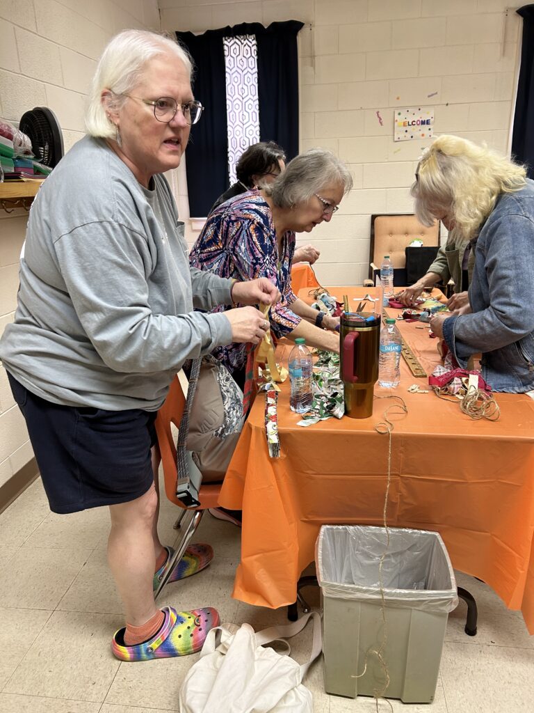 Ladies making cloth prayer garlands during a craft session.